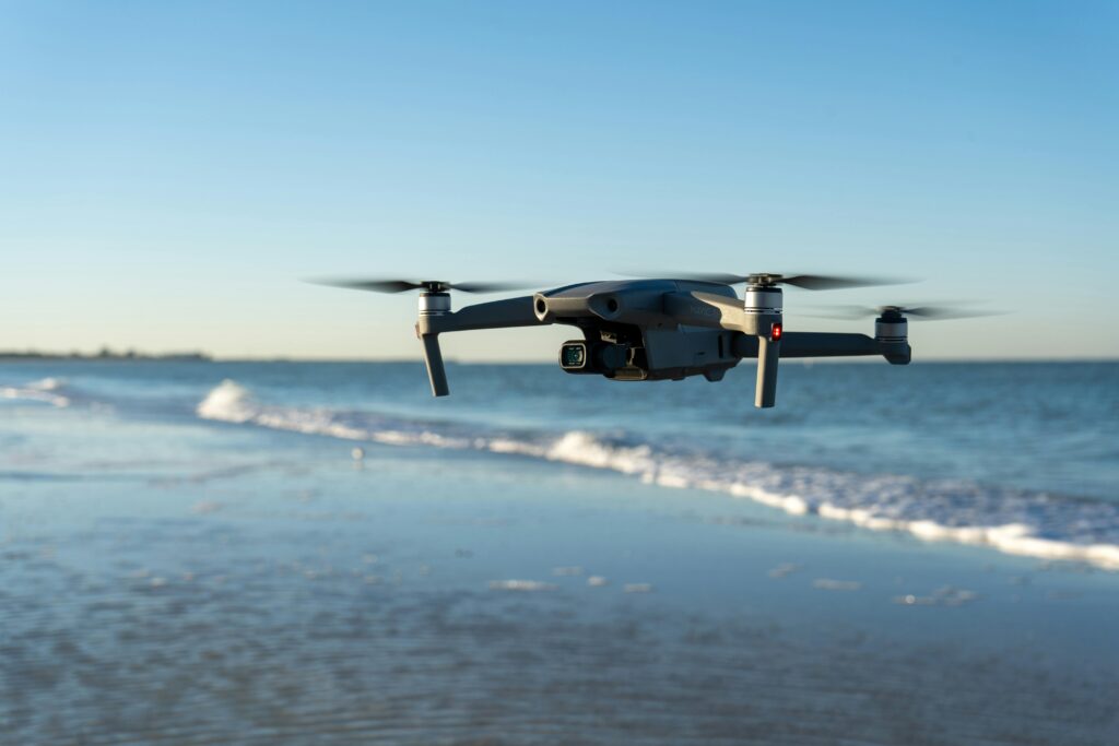 A drone flying over a tranquil beach with gentle waves in the background during sunset.
